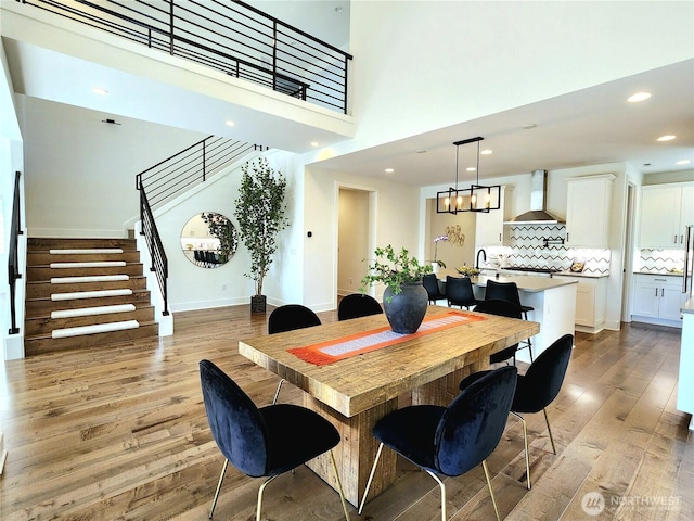dining room with stairs, recessed lighting, a towering ceiling, and light wood-type flooring