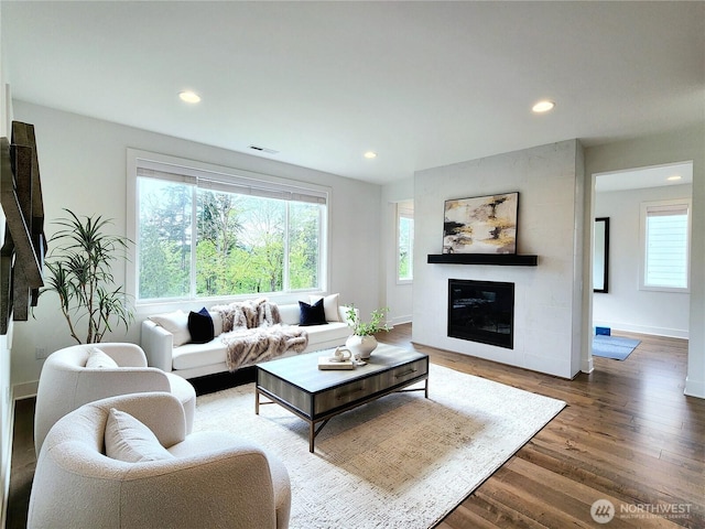 living room with plenty of natural light, wood finished floors, visible vents, and a fireplace