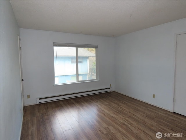 unfurnished room with a baseboard heating unit, wood finished floors, and baseboards