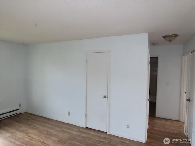 spare room featuring wood finished floors and a baseboard radiator