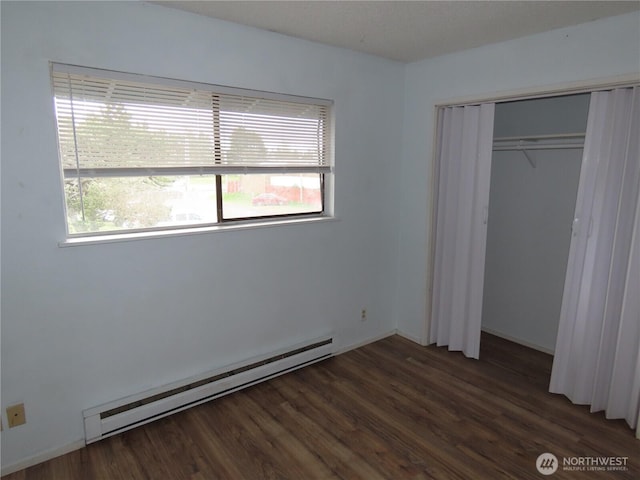 unfurnished bedroom featuring wood finished floors, a closet, and a baseboard radiator