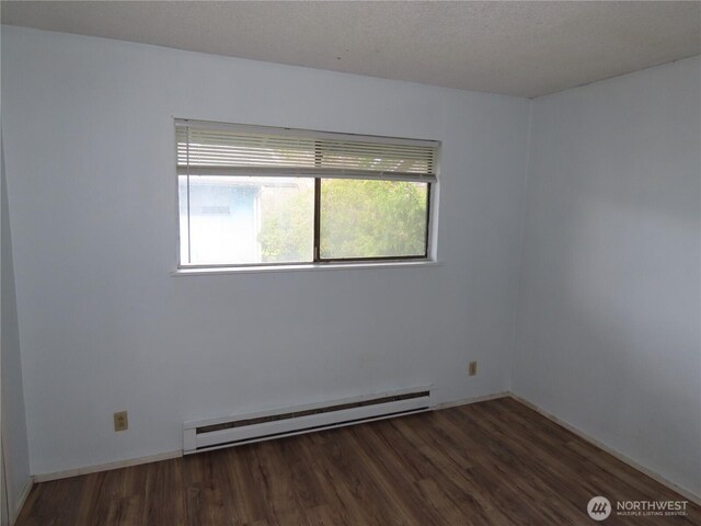 spare room with a baseboard heating unit, wood finished floors, and baseboards