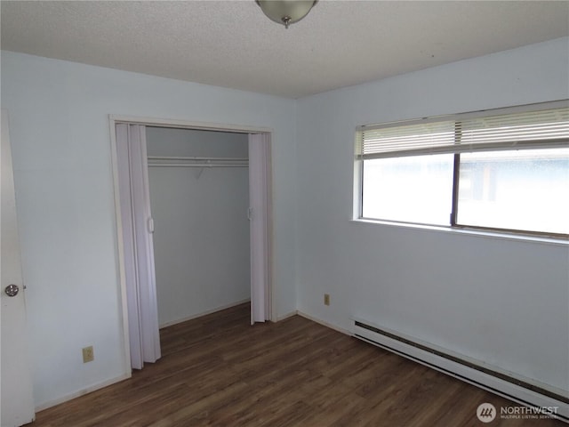 unfurnished bedroom with a textured ceiling, wood finished floors, baseboard heating, and a closet
