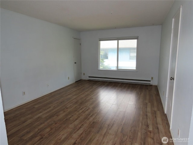 spare room featuring wood finished floors and baseboard heating