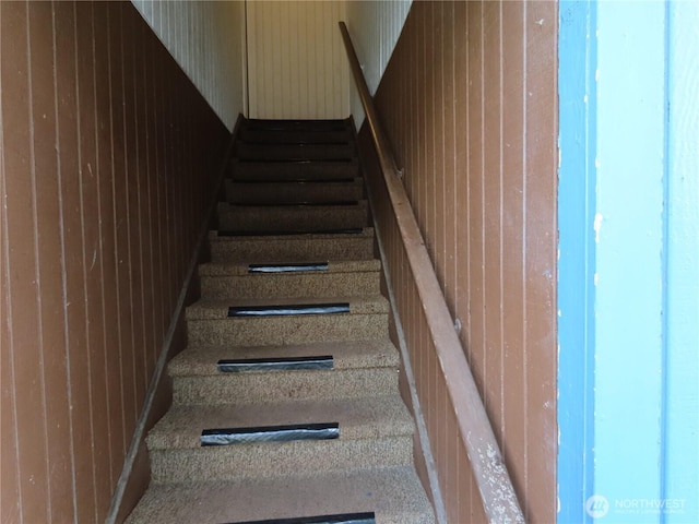 staircase featuring wood walls