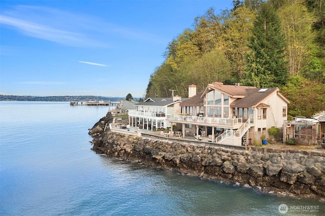 10885 Point Vashon Dr SW, Vashon, WA 98070 - rear view of house with a water view, a chimney, a sunroom, and a wooded view