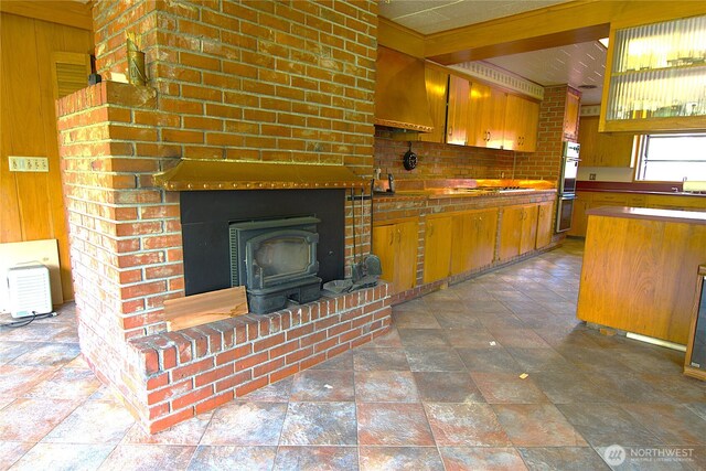 115 Kakela Rd, Winlock, WA 98596 - kitchen featuring double oven, stone finish flooring, wood walls, a sink, and a wood stove