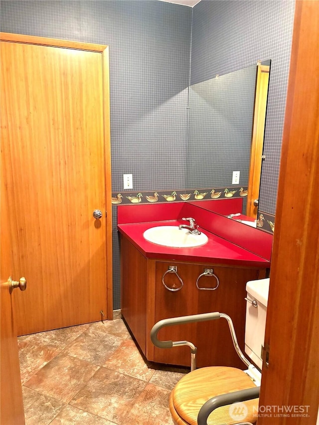 115 Kakela Rd, Winlock, WA 98596 - bathroom featuring stone finish floors, vanity, toilet, and wallpapered walls