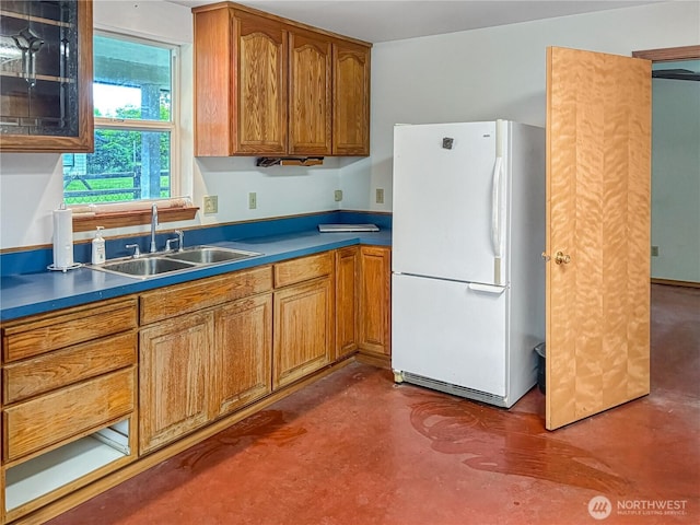 115 Kakela Rd, Winlock, WA 98596 - kitchen featuring freestanding refrigerator, a sink, finished concrete flooring, brown cabinetry, and dark countertops