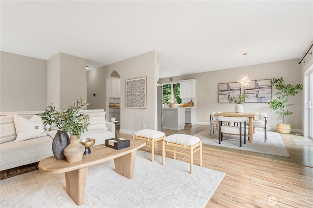 living room with light wood finished floors, arched walkways, and baseboards