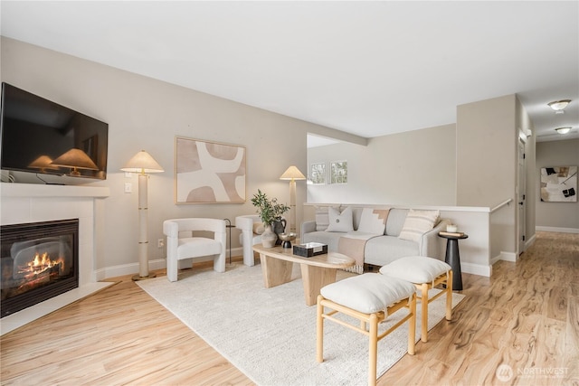 living room featuring a fireplace, wood finished floors, and baseboards