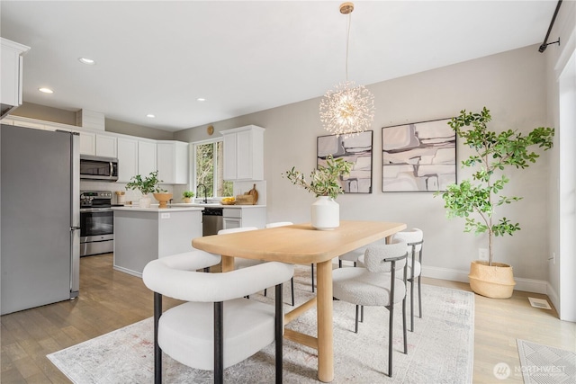 dining room featuring recessed lighting, a notable chandelier, baseboards, and light wood-style floors