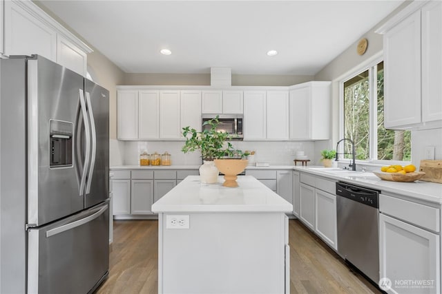 kitchen with stainless steel appliances, a kitchen island, decorative backsplash, and a sink