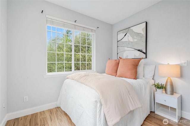 bedroom with baseboards, wood finished floors, and multiple windows