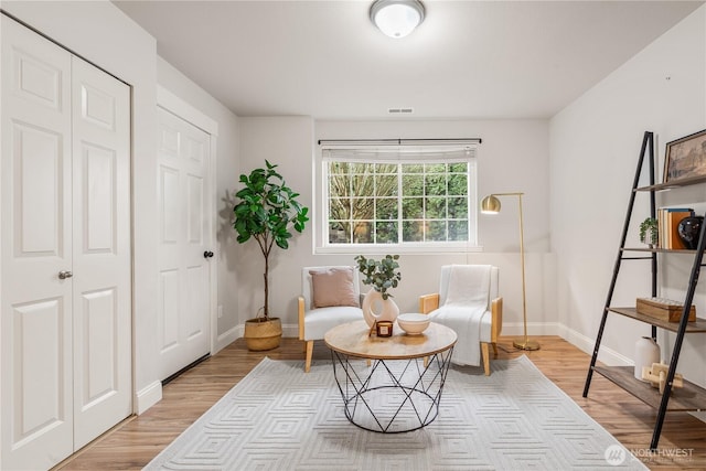 sitting room featuring visible vents, light wood-type flooring, and baseboards