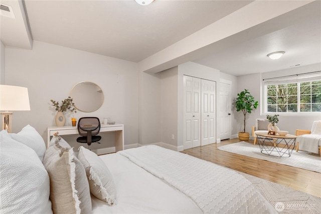 bedroom featuring baseboards, visible vents, wood finished floors, and a closet