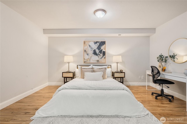 bedroom with baseboards, visible vents, and wood finished floors
