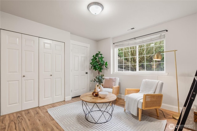living area with visible vents, baseboards, and light wood-type flooring