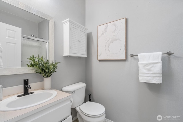 bathroom featuring toilet, vanity, and a shower stall