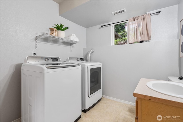 washroom featuring laundry area, a sink, baseboards, visible vents, and washer and clothes dryer