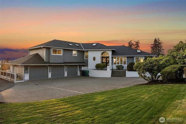 view of front of property featuring concrete driveway, a garage, and a front lawn