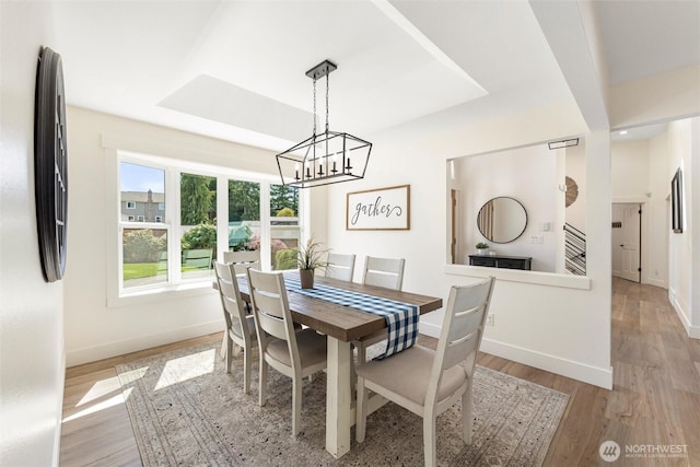 dining area featuring light wood finished floors, an inviting chandelier, and baseboards
