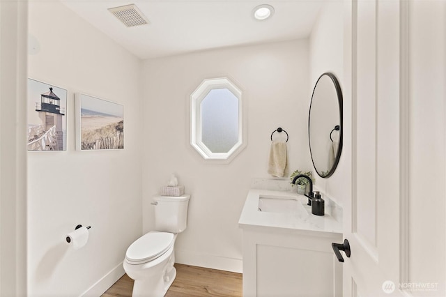 bathroom featuring visible vents, baseboards, toilet, vanity, and wood finished floors