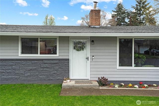 entrance to property featuring roof with shingles, stone siding, and a chimney