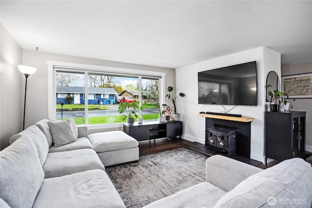living room featuring a wood stove, wood finished floors, and baseboards