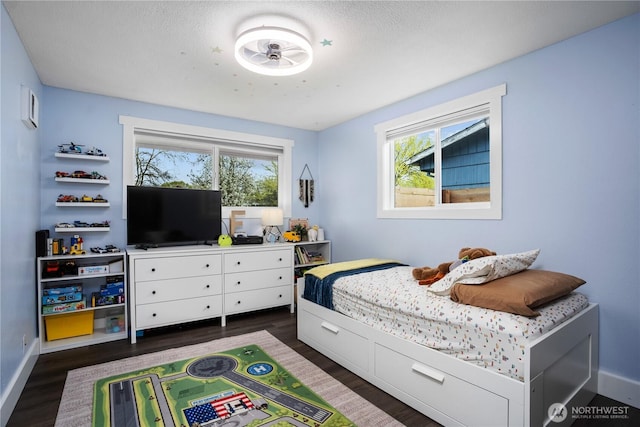 bedroom with dark wood-style flooring, baseboards, and multiple windows