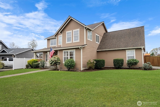 view of front of house featuring a front yard, fence, a shingled roof, and board and batten siding