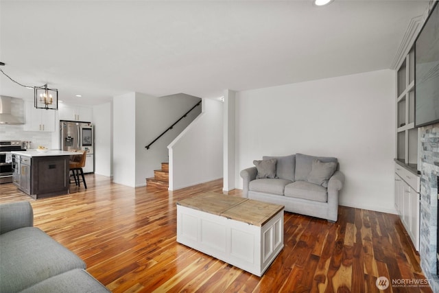 living room featuring a chandelier, recessed lighting, stairway, and light wood-type flooring