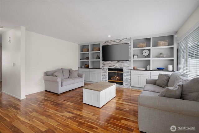 living room with built in features, baseboards, wood finished floors, and a fireplace
