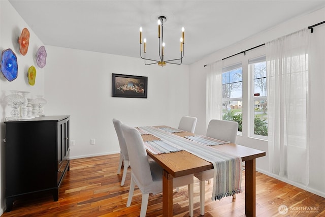 dining space featuring baseboards, an inviting chandelier, and light wood-style floors