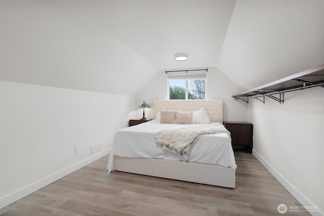bedroom with baseboards, wood finished floors, and lofted ceiling