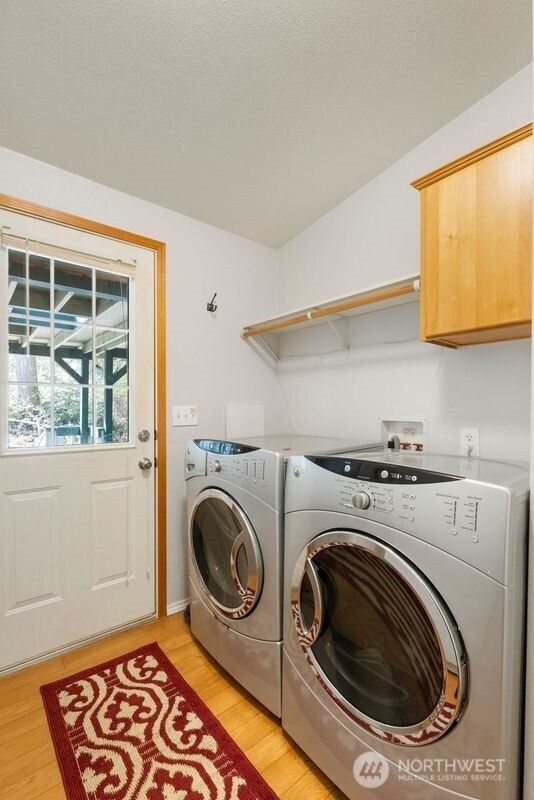 11712 114th Avenue Ct, Anderson Island, WA 98303 - clothes washing area featuring cabinet space, washing machine and dryer, and light wood-style floors