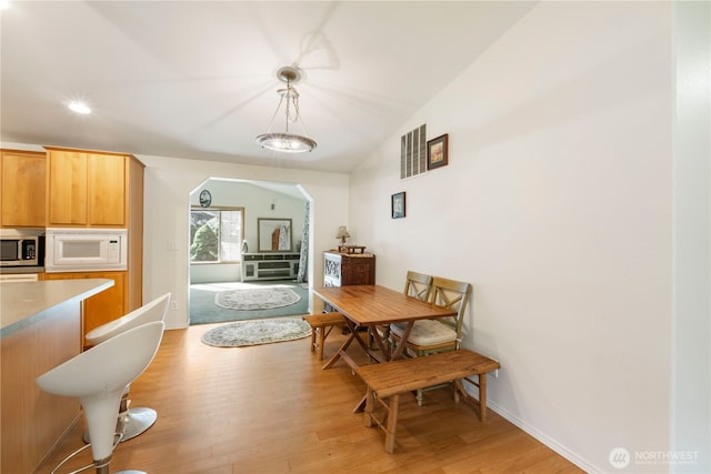 11712 114th Avenue Ct, Anderson Island, WA 98303 - dining area with arched walkways, baseboards, lofted ceiling, and light wood-type flooring