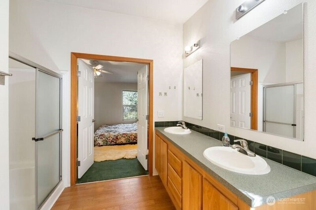 11712 114th Avenue Ct, Anderson Island, WA 98303 - bathroom with double vanity, a sink, a stall shower, and wood finished floors