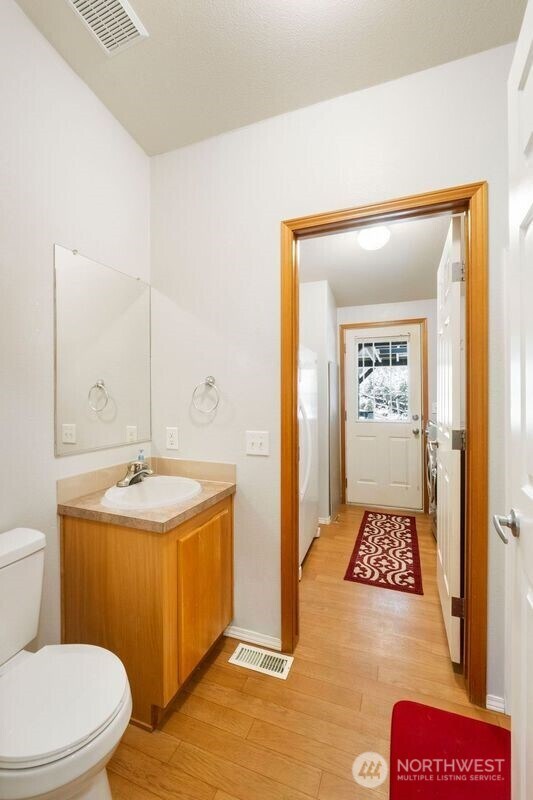 11712 114th Avenue Ct, Anderson Island, WA 98303 - bathroom with toilet, wood finished floors, vanity, and visible vents