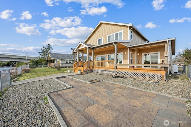 back of property with a fenced backyard, a wooden deck, and a lawn