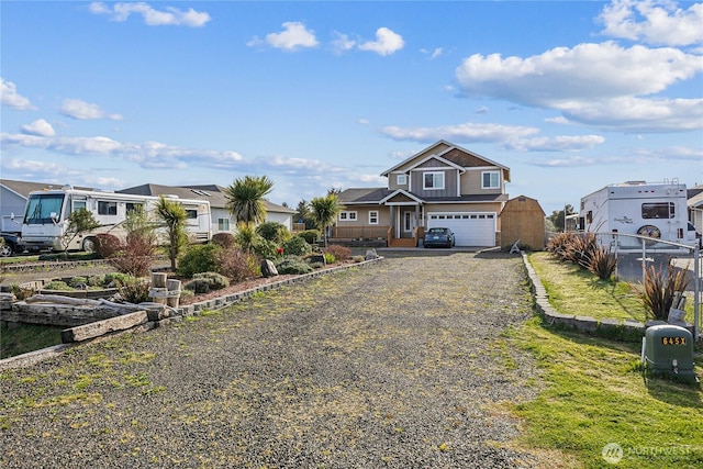 view of front of home with fence, a residential view, a garage, and gravel driveway