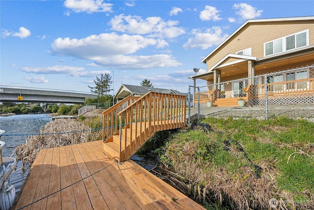 exterior space featuring a deck with water view and stairs