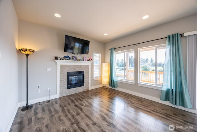 unfurnished living room with baseboards, recessed lighting, a glass covered fireplace, and wood finished floors