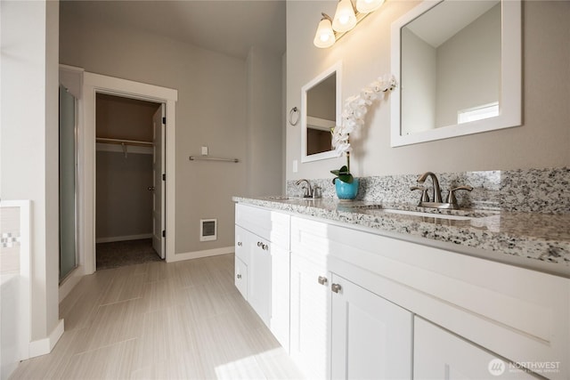 full bath featuring double vanity, a sink, a spacious closet, and visible vents
