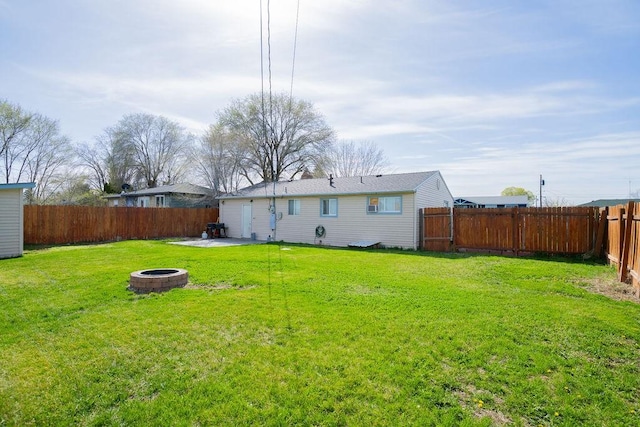 rear view of property featuring a patio area, a fenced backyard, a fire pit, and a lawn