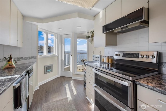 kitchen with a water view, decorative backsplash, range with two ovens, under cabinet range hood, and dark wood-type flooring