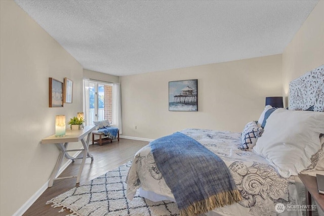 bedroom with wood finished floors, baseboards, and a textured ceiling