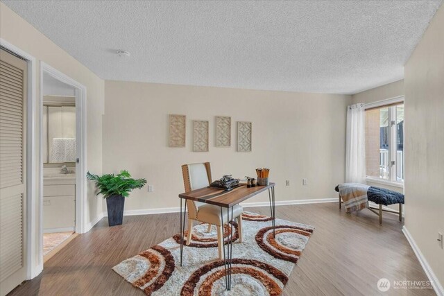 office space with baseboards, wood finished floors, and a textured ceiling