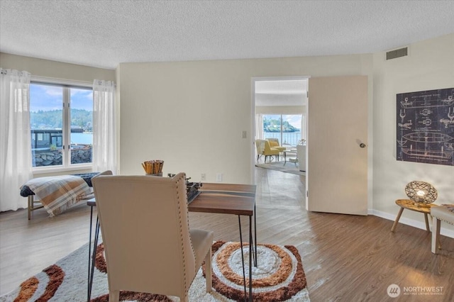 dining area featuring wood finished floors, visible vents, and a healthy amount of sunlight