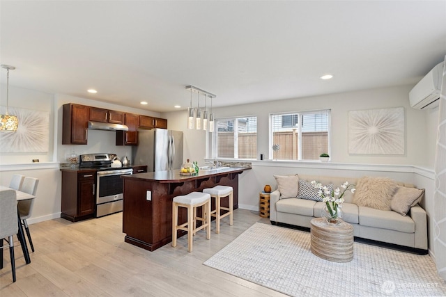 8015 Beacon Ave S Unit A, Seattle, WA 98118 - kitchen featuring a wall mounted air conditioner, light wood-style floors, a breakfast bar, and appliances with stainless steel finishes